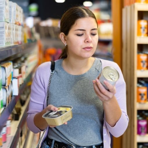 Woman comparing dog food products in a pet store aisle